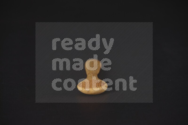 Cinnamon powder in a wooden spoon on a black background