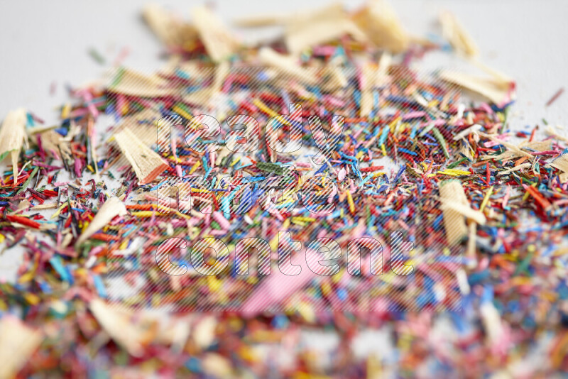 This image showcases a vibrant multicolored pencil shavings scattered on grey background
