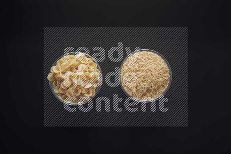 Different pasta types in glass bowls on black background