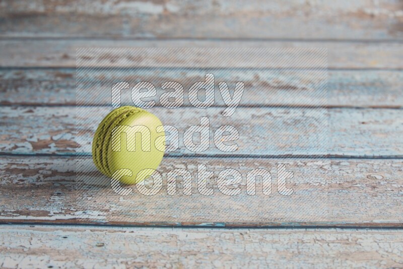 45º Shot of Green Pistachio macaron on light blue wooden background