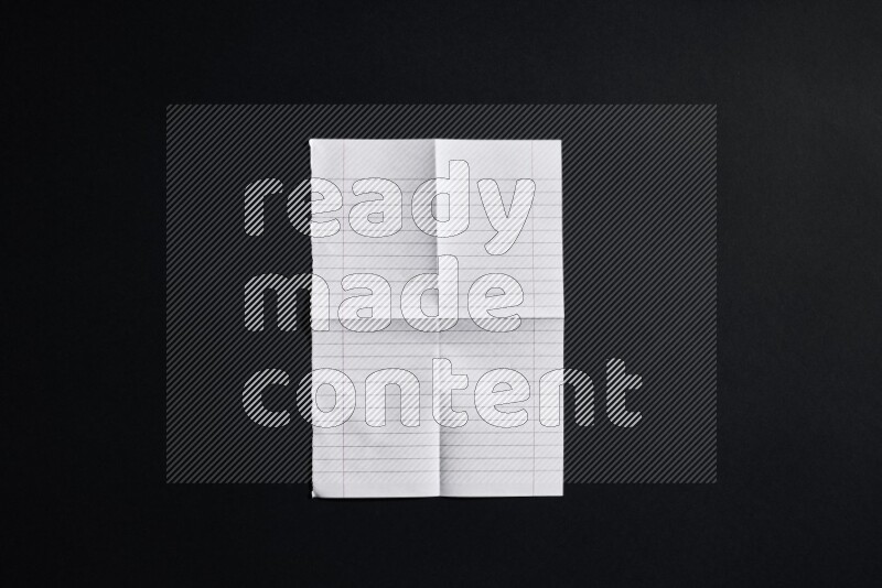 Folded notebook sheet on black background