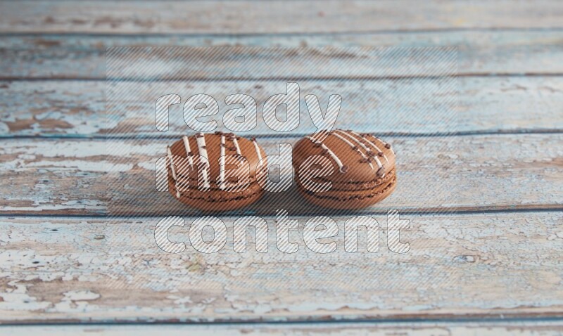 45º Shot of two Brown white  Chocolate Caramel macarons on light blue wooden background
