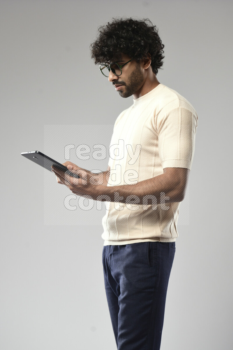 A man wearing casual standing and browsing on a tablet on white background