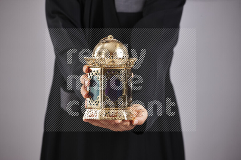A woman in black abaya holding different ramadan lanterns in different positions
