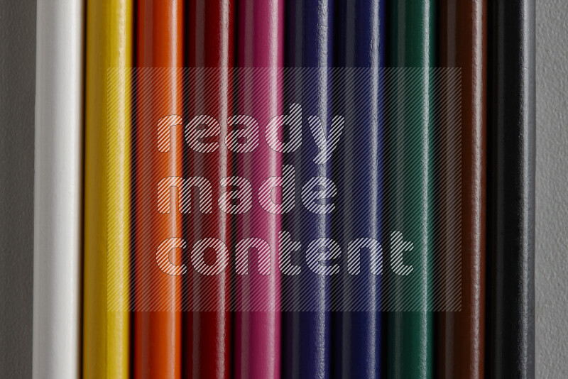 مجموعة من أقلام الرصاص الملونة مرتبة لتعرض تدرجا من الألوان المختلفة علي خلفية رمادية