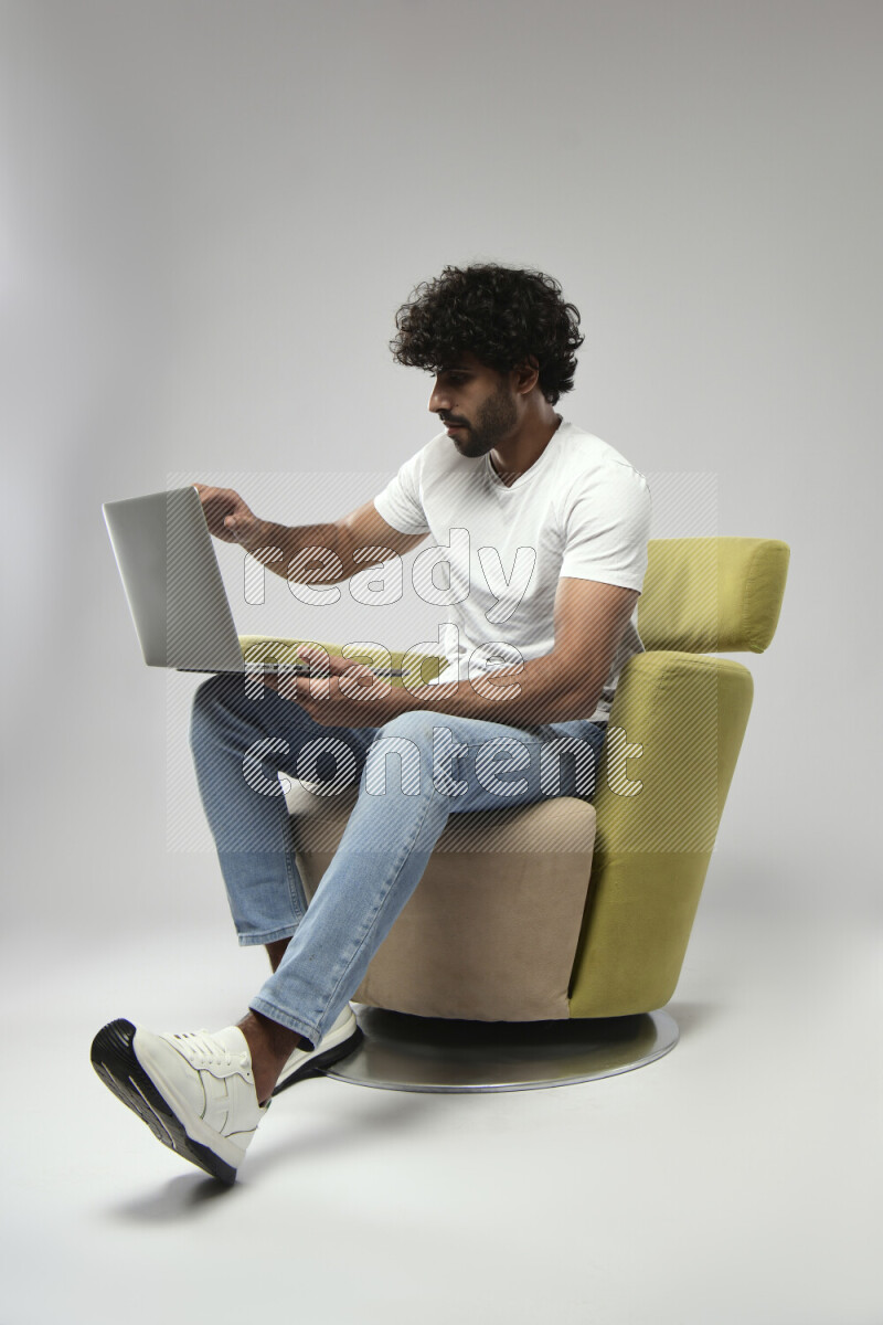 A man wearing casual sitting on a chair working on a laptop on white background