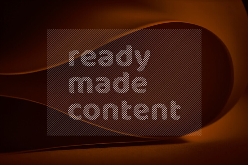 An abstract art piece displaying smooth curves in orange gradients created by colored light