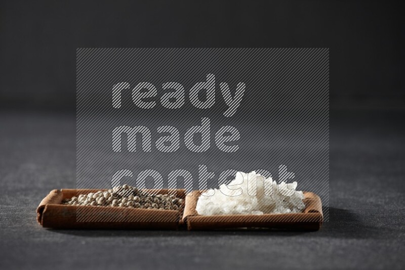 2 squares of cinnamon sticks full of white pepper and salt on black flooring