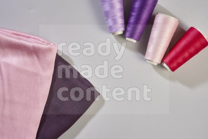 Multicolored fabrics with sewing supplies on grey background