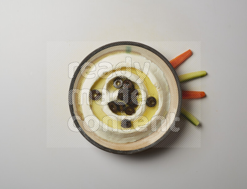 Lebnah garnished with sliced olives in a pottery plate on a white background