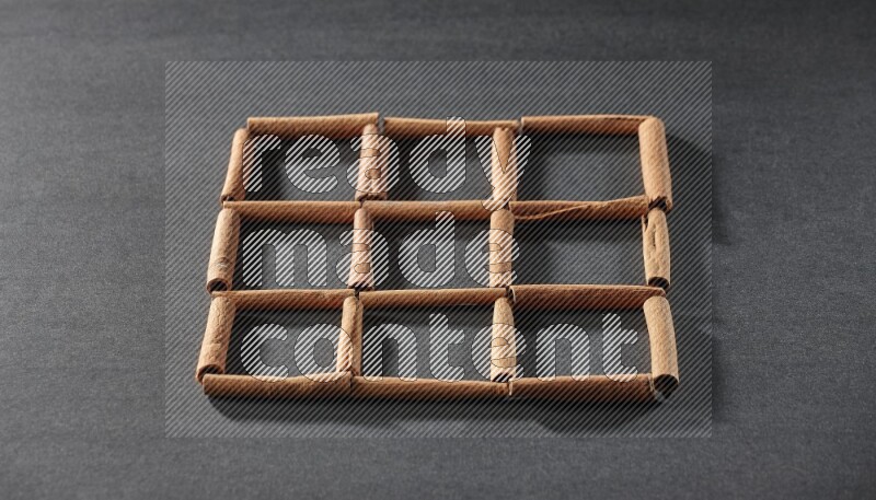 9 empty squares of cinnamon sticks on black flooring