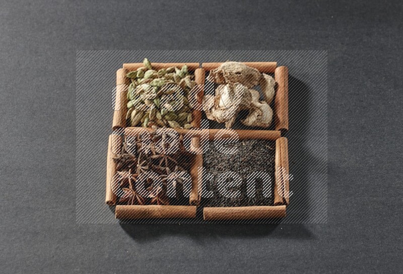4 squares of cinnamon sticks full of tea, star anise, dried ginger and cardamom on black flooring