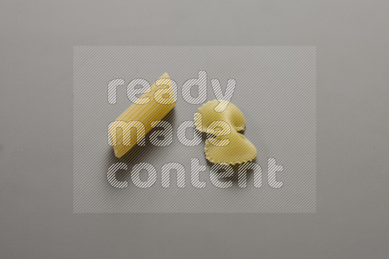 Penne pasta with other types of pasta on grey background