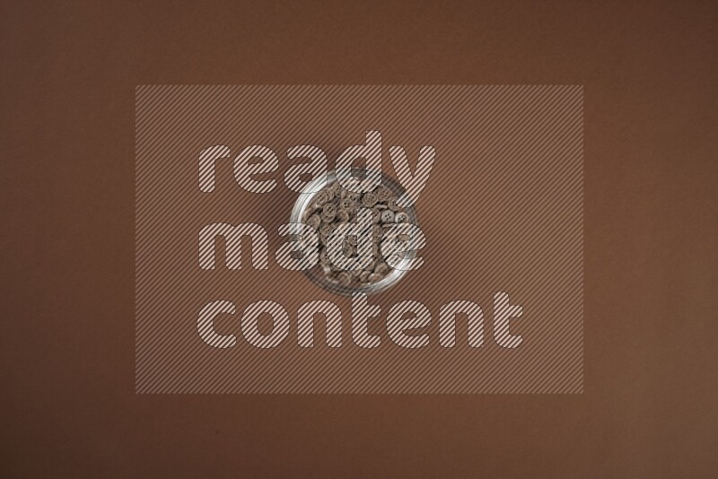 Brown buttons in a glass bowl on brown background