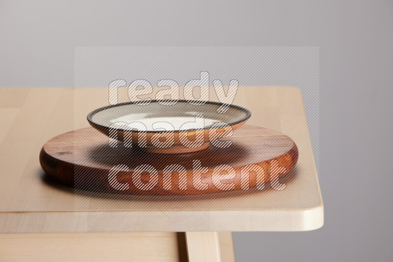 multi-colored pottery Plate placed on a dark colored wooden tray on the edge of wooden table