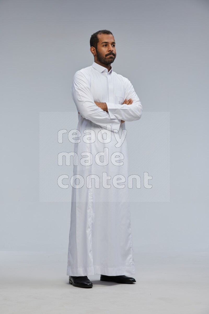 Saudi man wearing Thob standing with crossed arms on Gray background