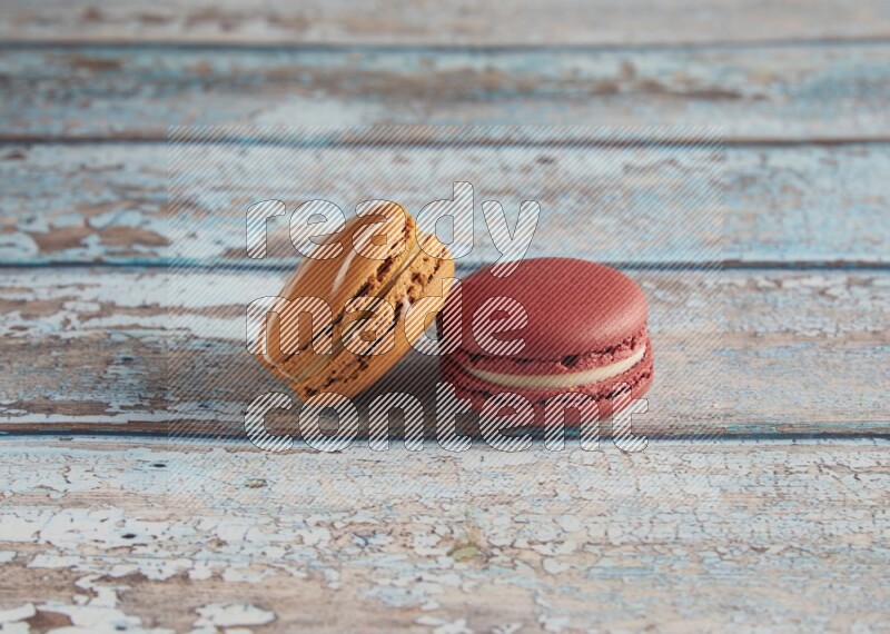 45º Shot of of two assorted Brown Irish Cream, and Red Velvet macarons on light blue background