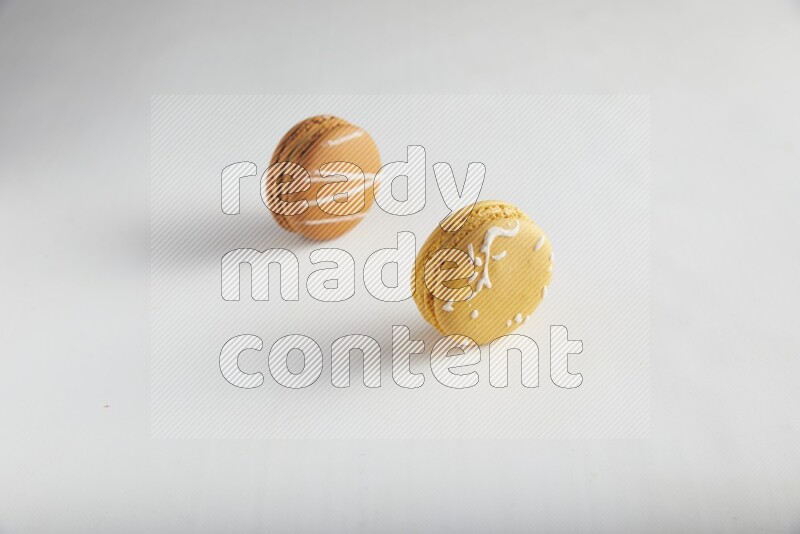 45º Shot of of two assorted Brown Irish Cream, and Yellow Piña Colada macarons on white background