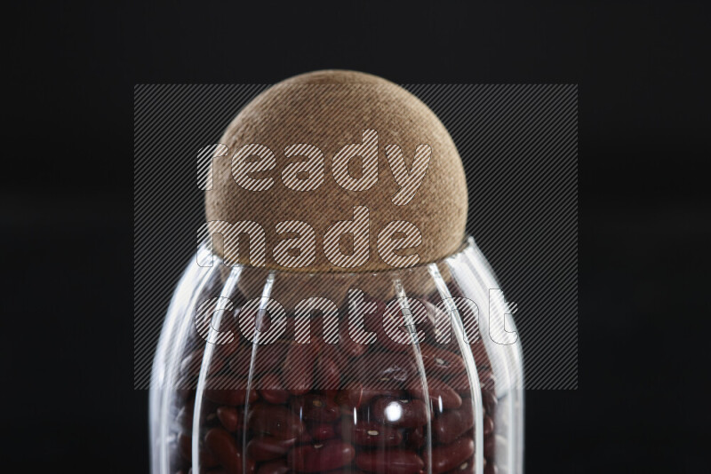 Red kidney beans in a glass jar on black background