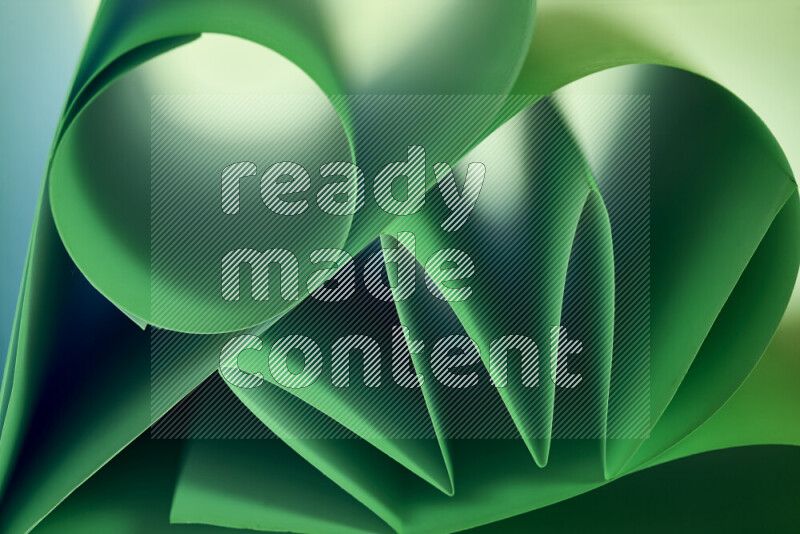 An artistic display of paper folds creating a harmonious blend of geometric shapes, highlighted by soft lighting in green tones