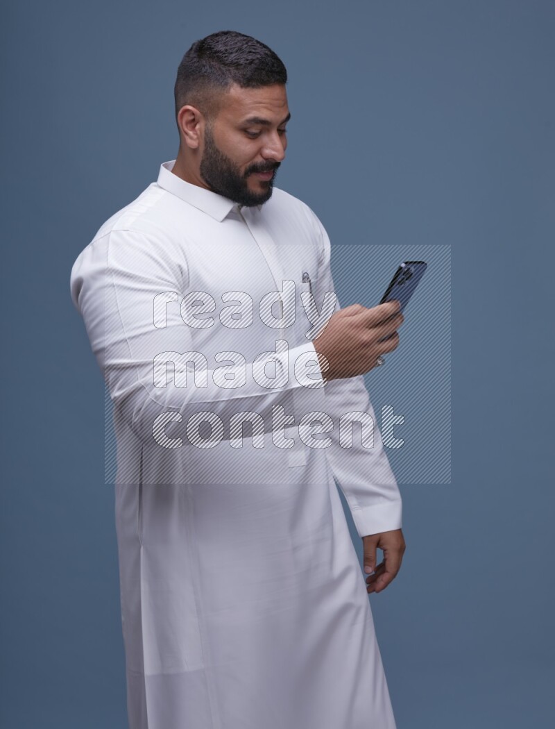 A man Texting on Blue Background wearing Saudi Thob
