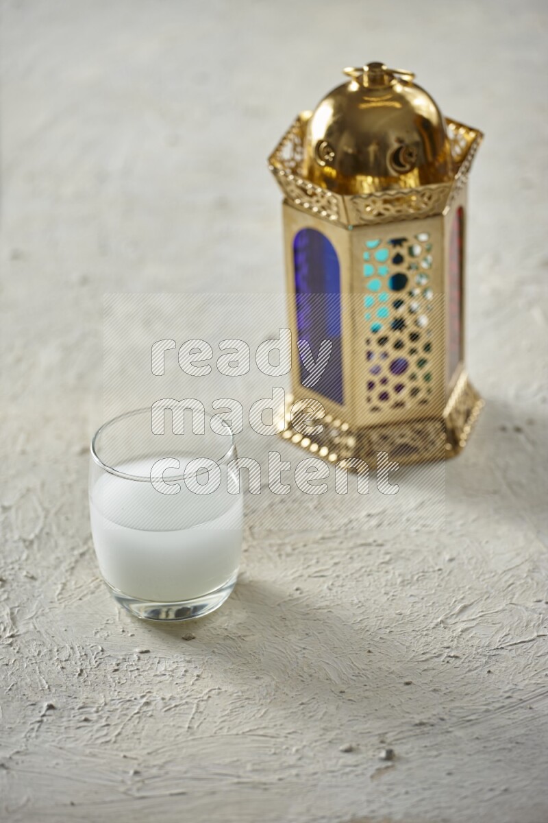 A golden lantern with different drinks, dates, nuts, prayer beads and quran on textured white background