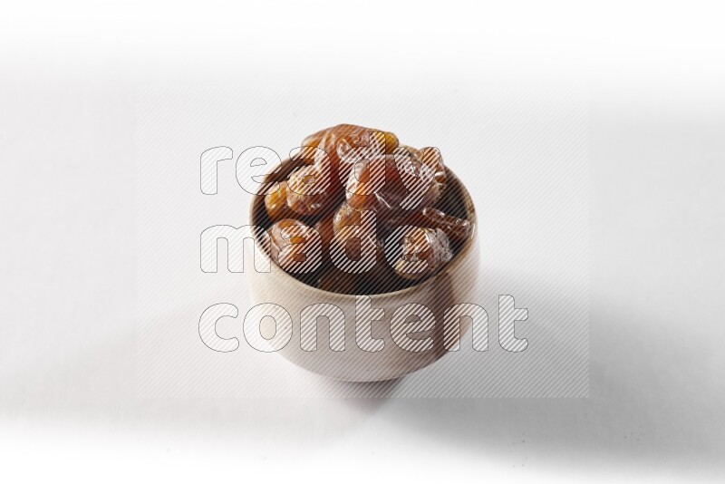 Dates in a beige pottery bowl on white background