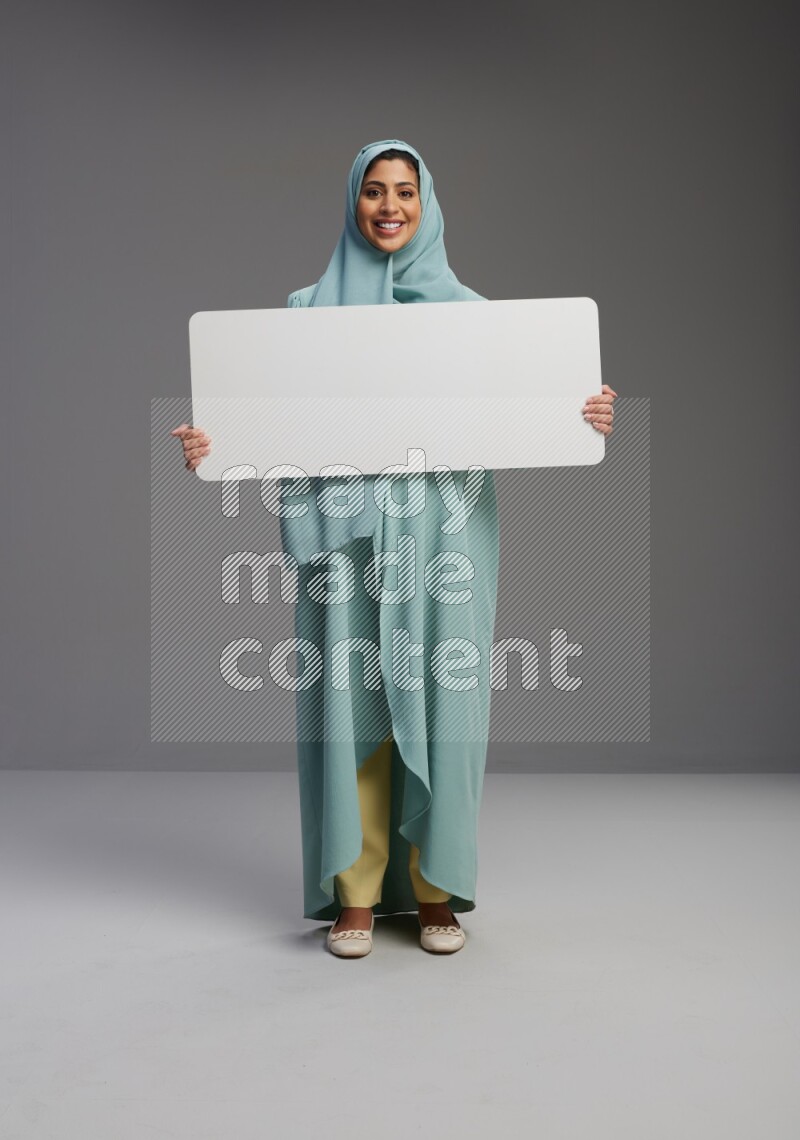 Saudi Woman wearing Abaya standing holding board on Gray background