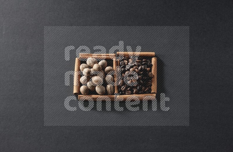 مربعان من أعواد القرفة ممتلئان بحبوب القهوة وجوزة الطيب علي خلفية سوداء