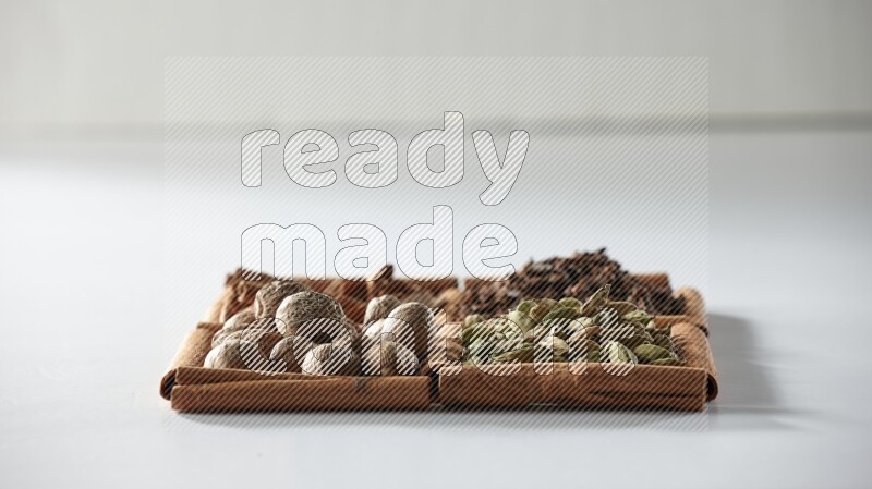 4 squares of cinnamon sticks full of cardamom, cinnamon, cloves and nutmeg on white flooring