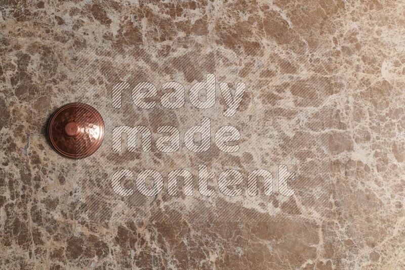 A small copper pot on beige marble background