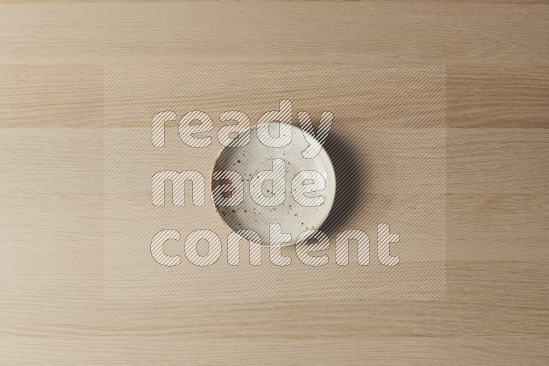 A multicolored pottery plate on light wooden background