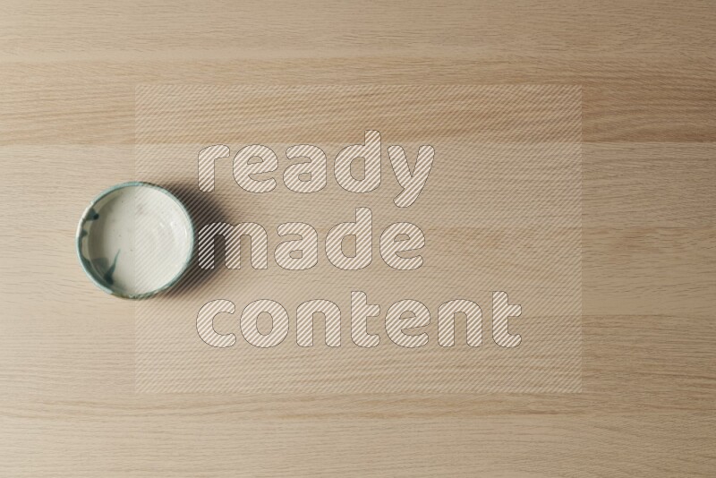 A multicolored pottery bowl on light wooden background