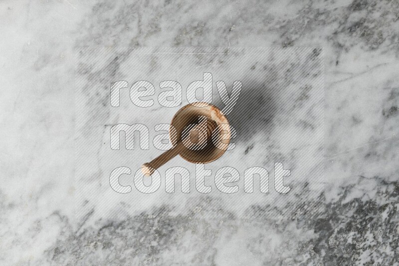 Beige pottery bowl with wooden honey dipper in it on grey marble background
