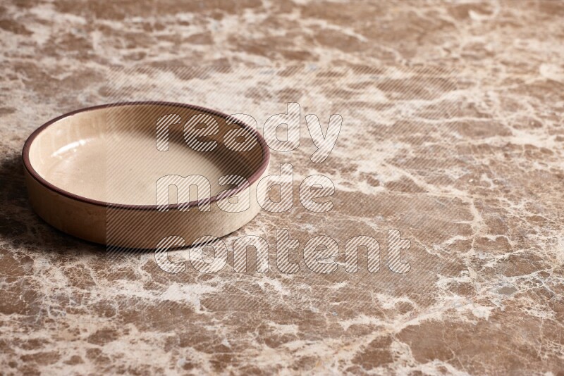 A beige pottery oven plate on beige marble background