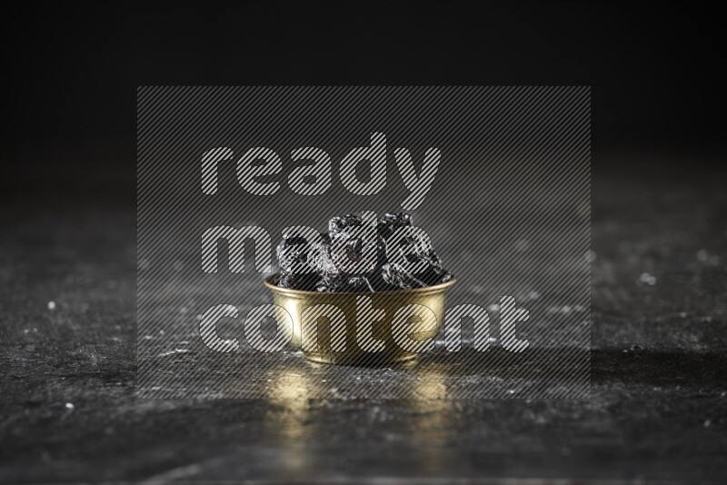 Dried fruits in a metal bowl in a dark setup