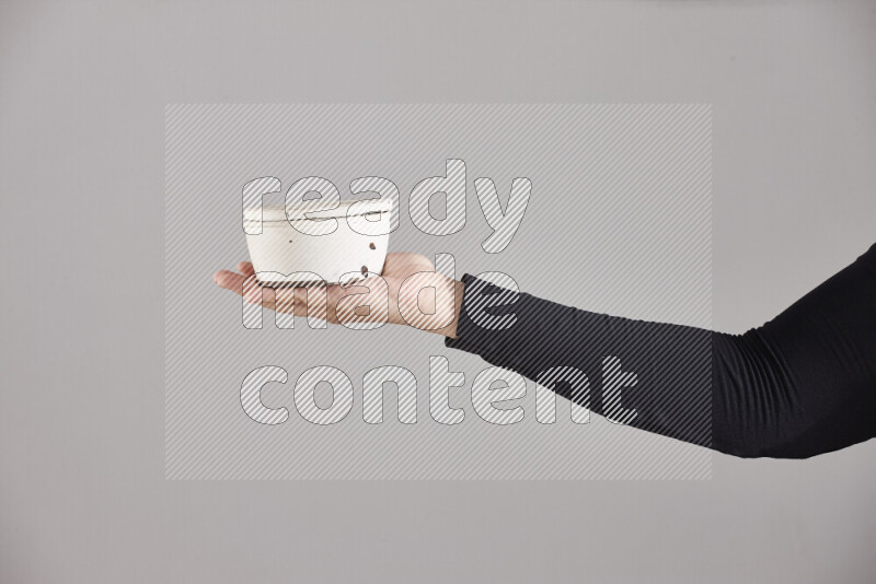 A woman in black abaya holding different pottery essentials in different positions