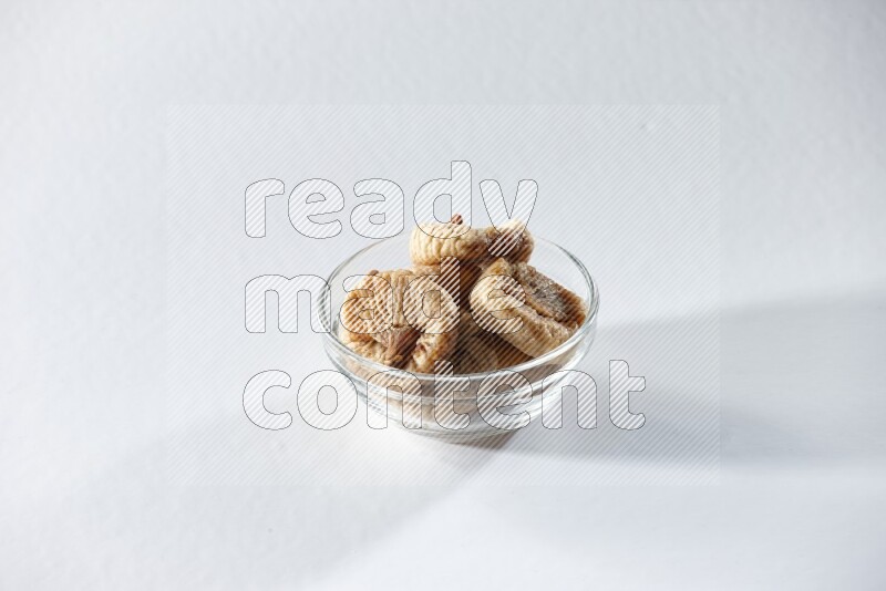A glass bowl full of dried figs on a white background in different angles