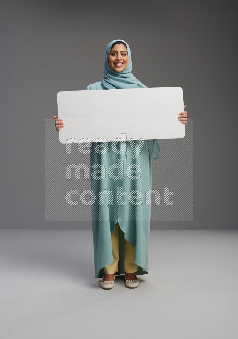 Saudi Woman wearing Abaya standing holding board on Gray background