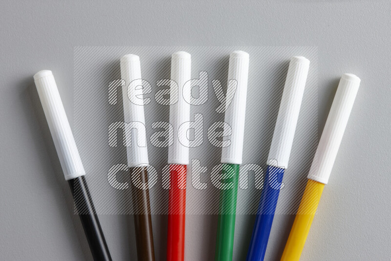 An arrangement of coloring pens in different colors on grey background