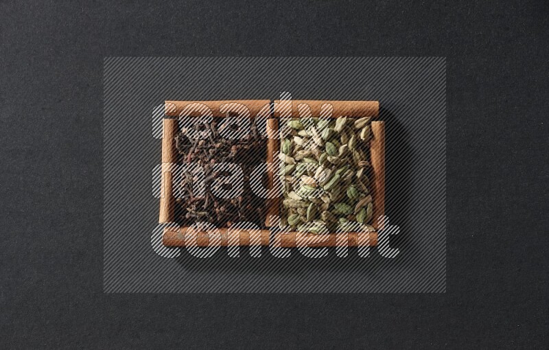 2 squares of cinnamon sticks full of cardamom and cloves on black flooring