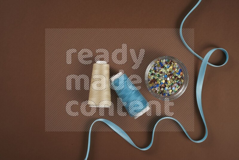 A blue collection of sewing and tailoring tools arranged on a brown background