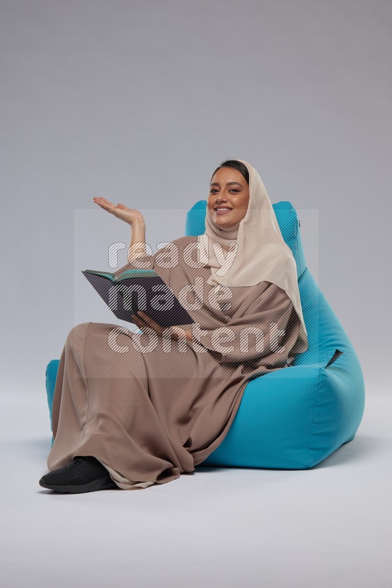 A woman sitting on a blue beanbag and reading a book