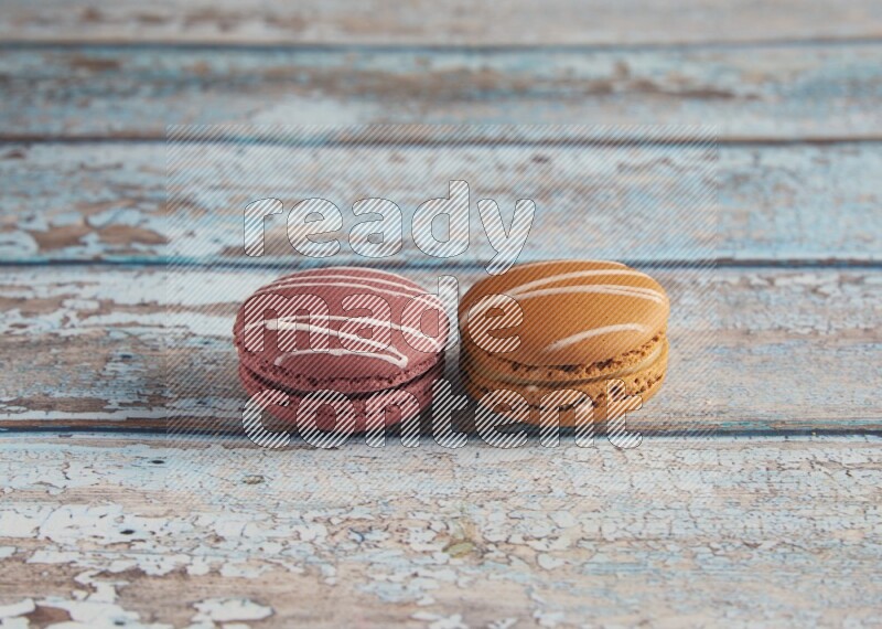 45º Shot of of two assorted Brown Irish Cream, and Red Poppy Flower macarons  on light blue background