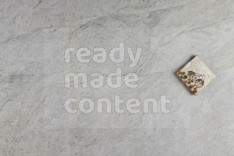 A decorative pottery coaster on grey marble background