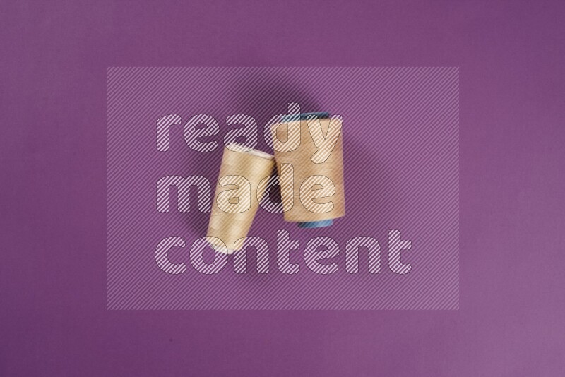 A beige collection of sewing and tailoring tools arranged on a purple background