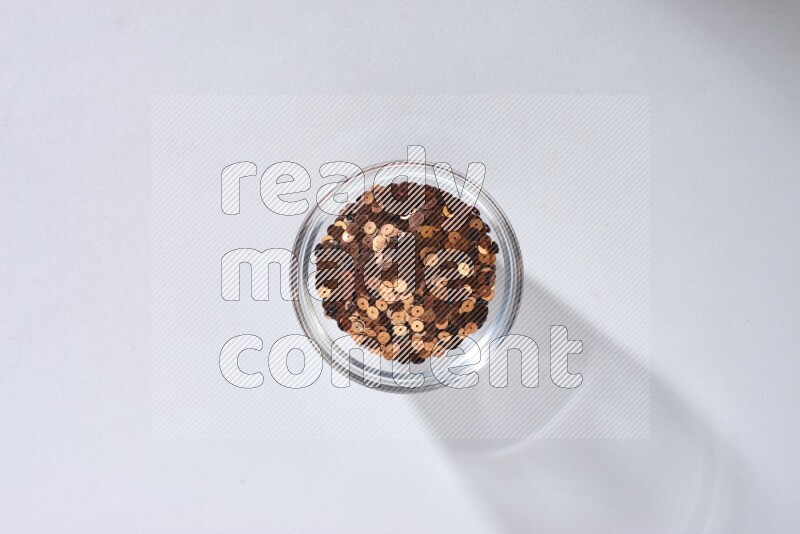 Colored flat sequins in a glass bowl on grey background