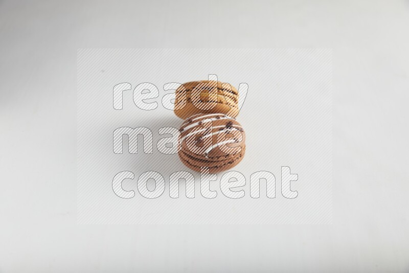 45º Shot of of two assorted Brown Irish Cream, and Brown white Chocolate Caramel macarons on white background