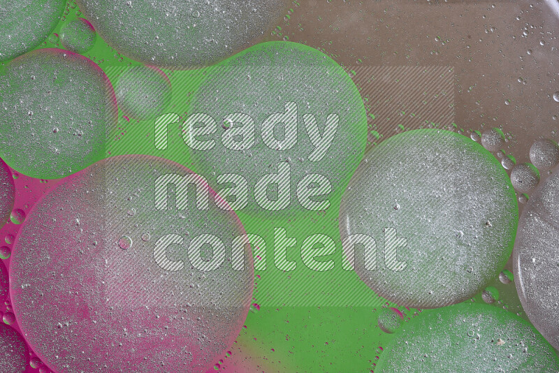 Close-ups of abstract oil bubbles on water surface in shades of brown, green and pink