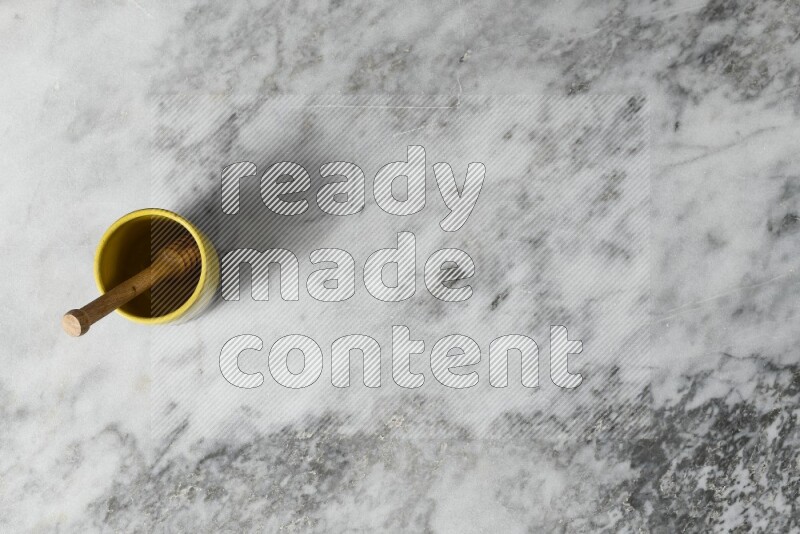 Multicolored pottery cup with wooden honey dipper in it on grey marble background